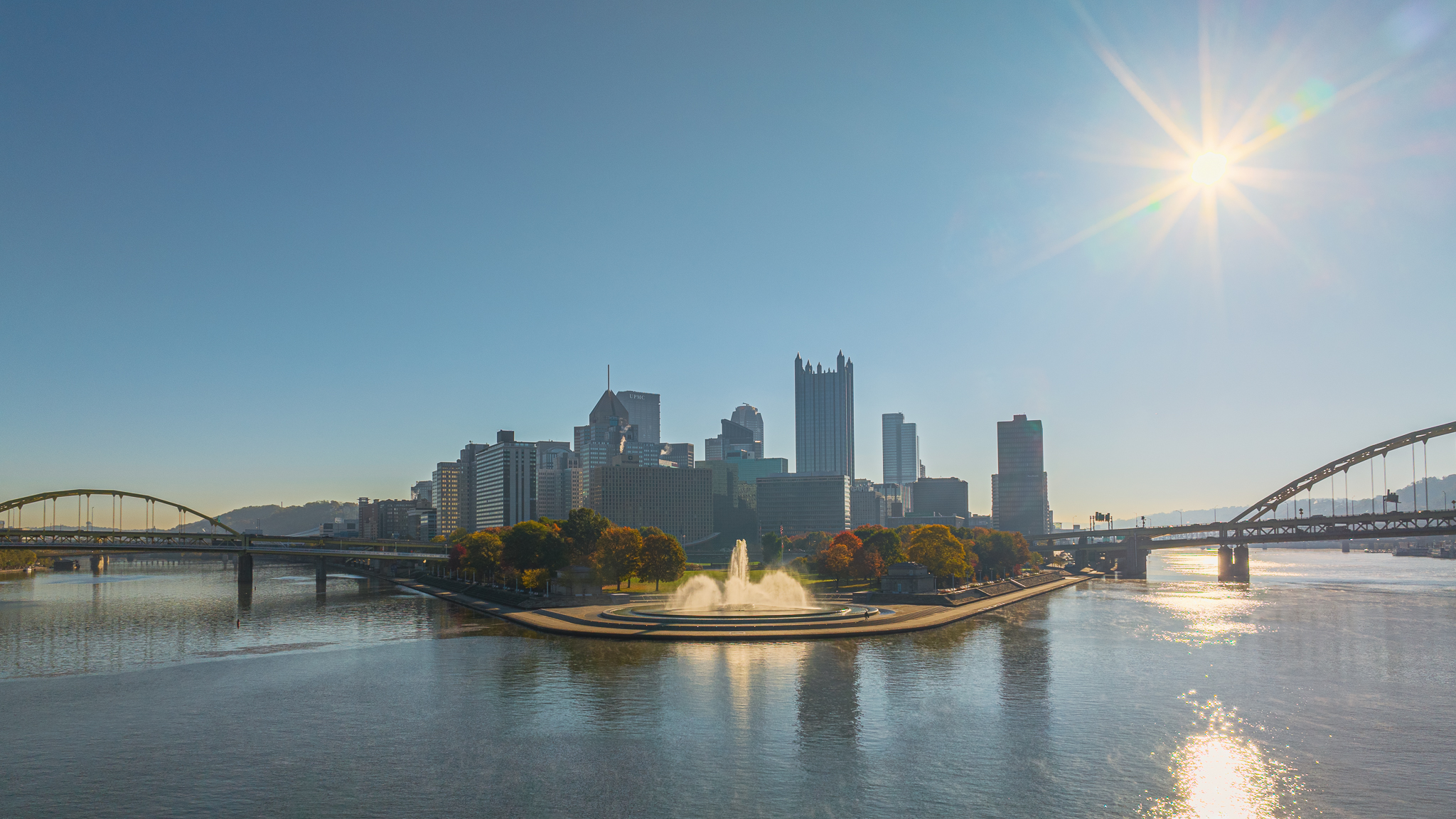 Wide aerial view of Point State Park with sun flare and Pittsburgh skyline