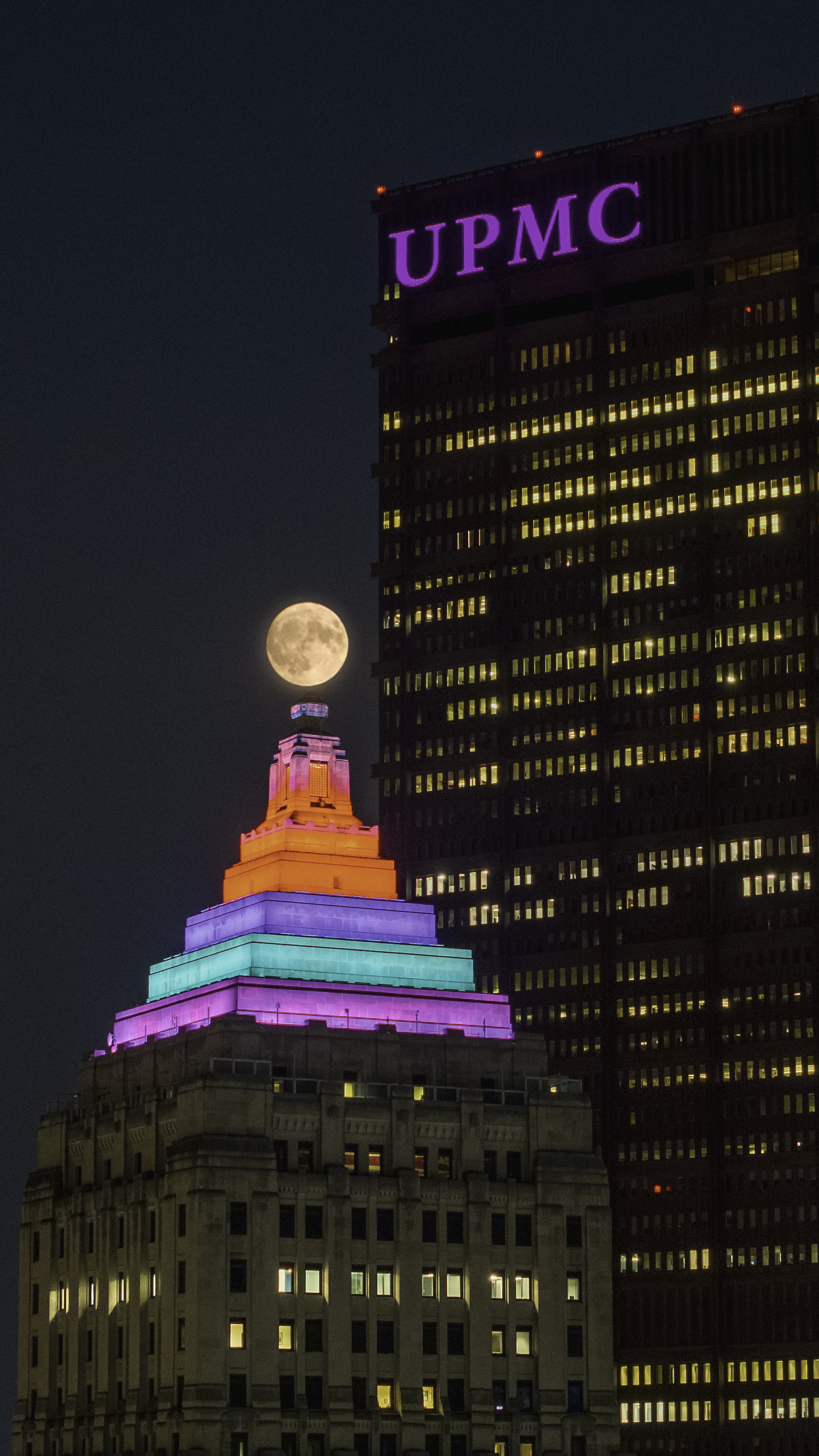 UPMC tower at night with full moon rising over Pittsburgh